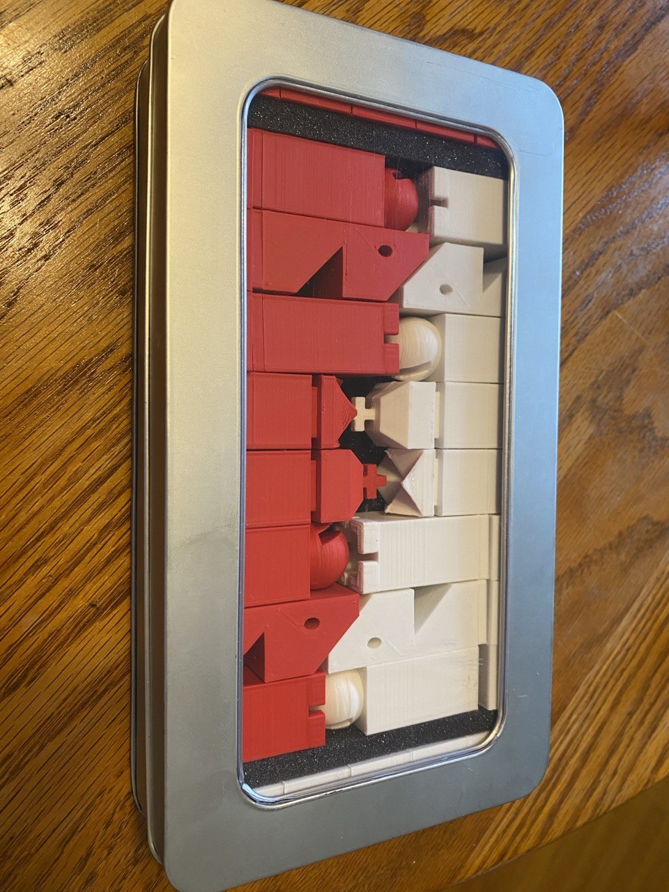 The finished red and white pieces nested snugly in the foam of a repurposed metal Pez-dispenser display tin.