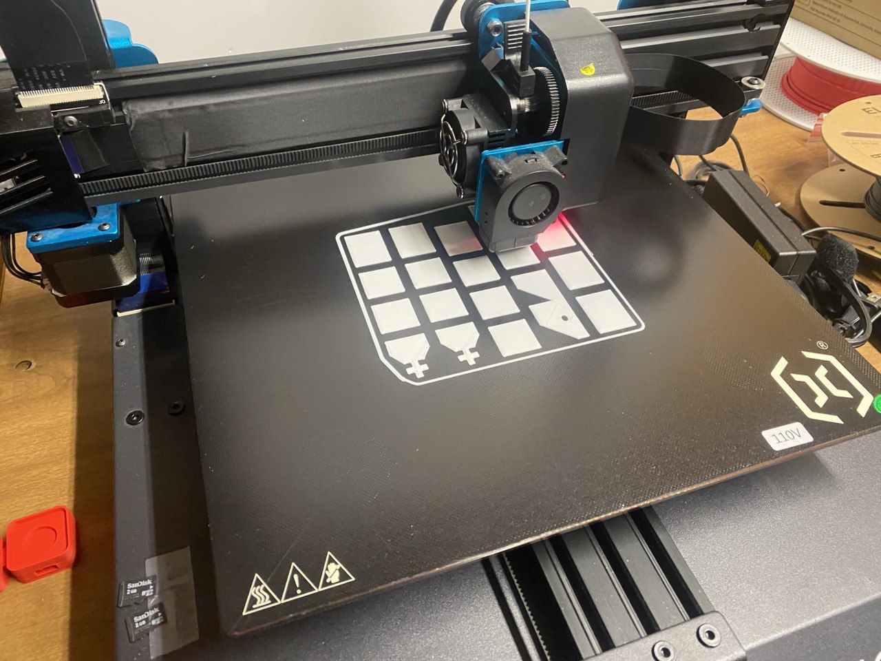 A print just getting started: the first-layer outlines of about sixteen pieces laid out across the build plate, the cross-topped king and crown-topped queen already recognizable.