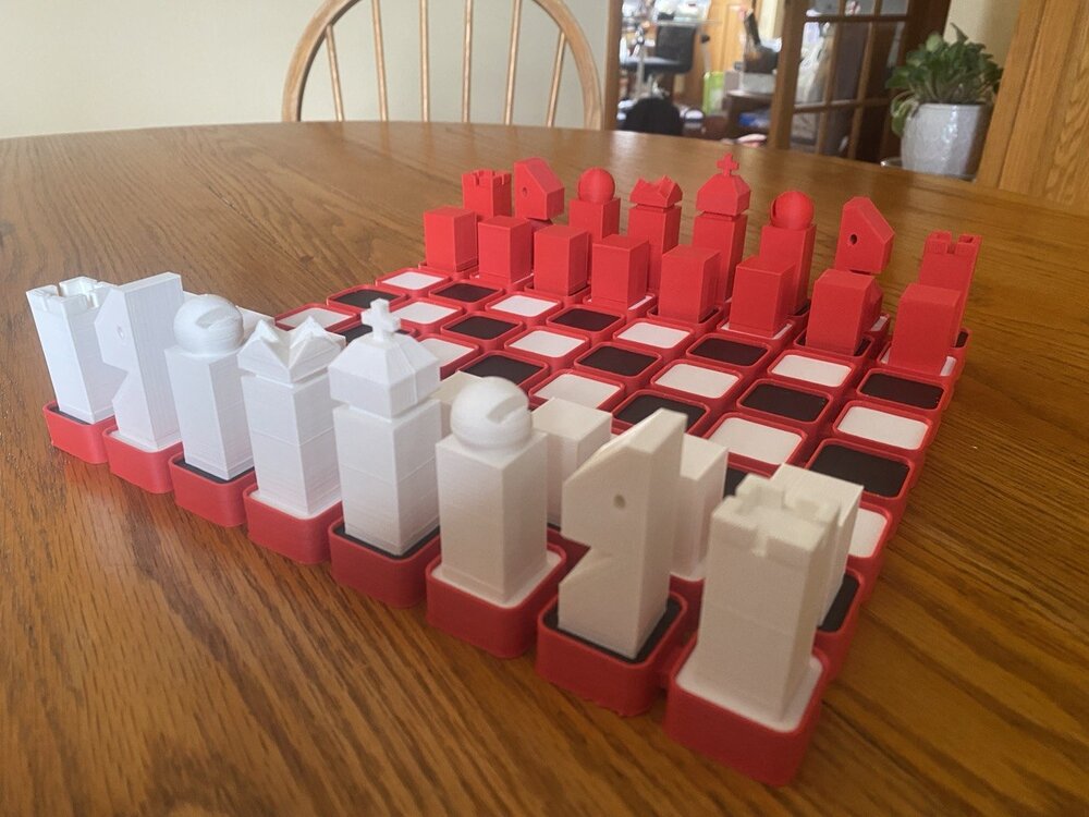 A red and white low-poly 3D-printed chess set on its red board